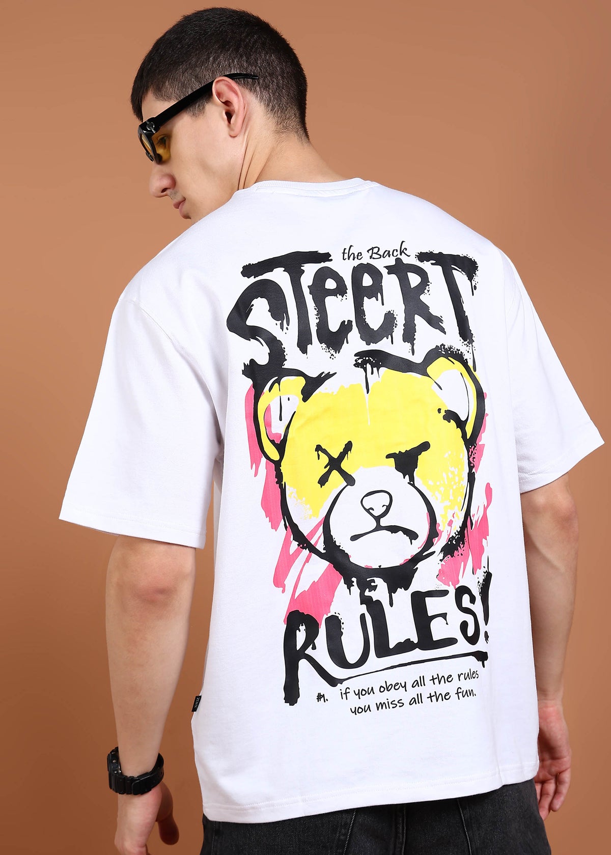A person wearing an oversized white t-shirt with a graphic of a bear and the text 'STREET RULES' on the back.