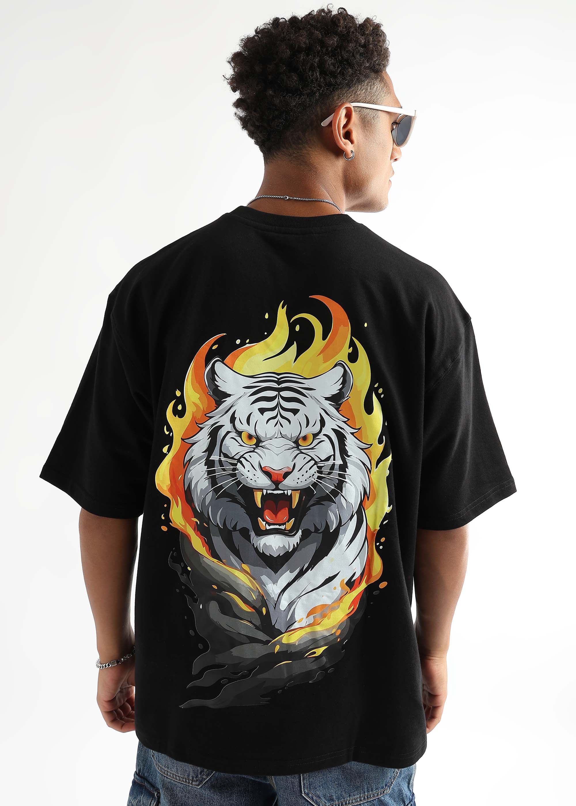 A person wearing an oversized black t-shirt with a graphic of a white tiger with flames around it.